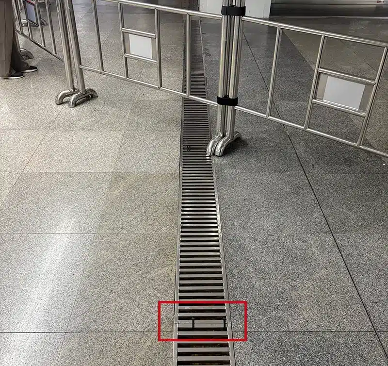 Black cable ties used to fix sectional drain covers in subway station