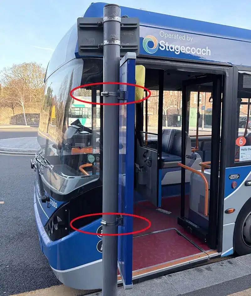 Stainless steel hose clamps fixing a vertical pole at a UK bus stop