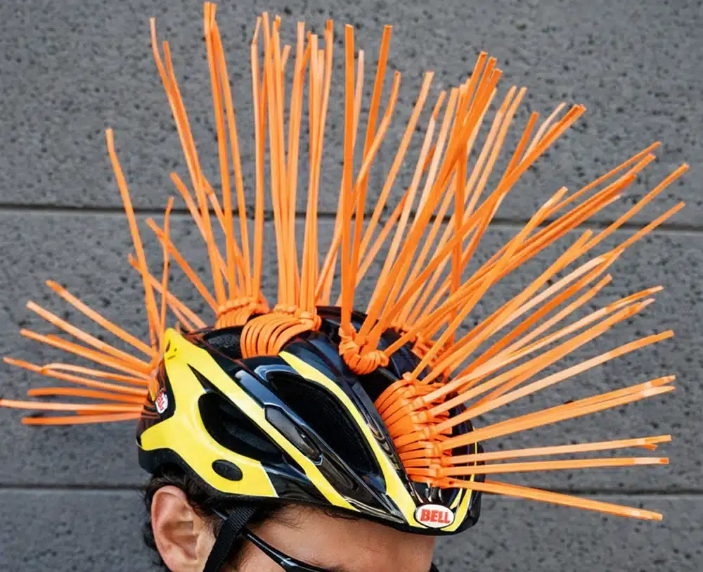 Cable ties creating a spiked helmet decoration, with orange zip ties threaded through bike helmet vents
