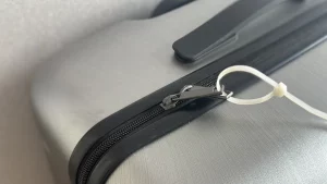 A cable ties securing two luggage zipper pulls together to show if the suitcase has been opened