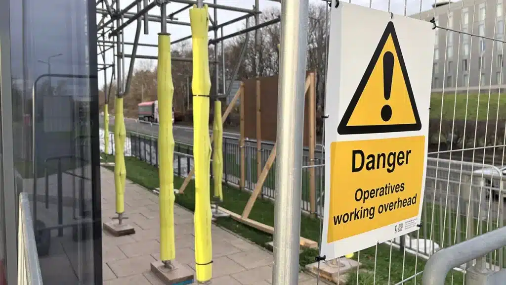 Cable ties securing yellow foam padding on scaffold poles to prevent impact and slipping.