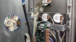 Cable ties grouping thin signal wires behind an elevator button panel