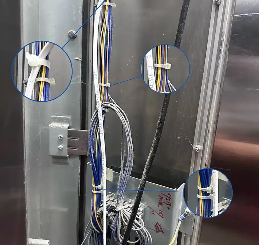 Cable ties fixing vertical wire bundles behind an elevator button panel
