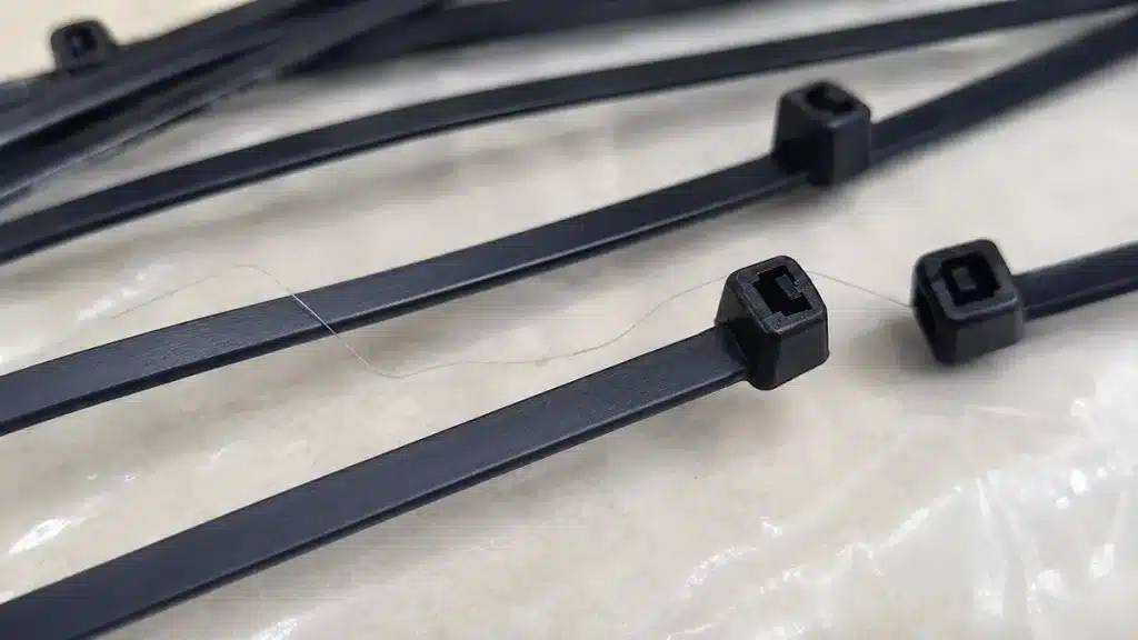 Hair-like nylon strand on black cable ties caused by injection molding stringing
