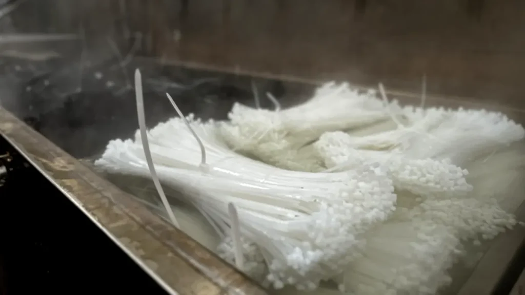 White PA66 nylon cable ties undergoing warm-water moisture conditioning after injection molding